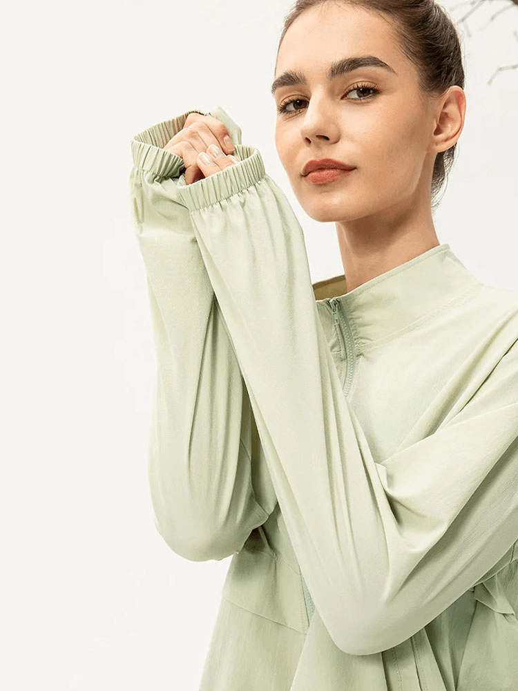 Woman wearing a green UV protection running windbreaker with long sleeves and turn-down collar, emphasizing outdoor activewear style.